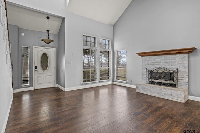 unfurnished living room featuring high vaulted ceiling, a brick fireplace, dark wood-style flooring, and baseboards