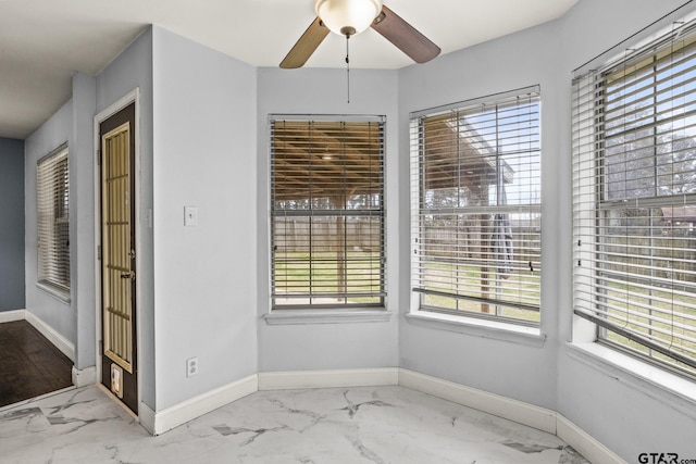 unfurnished dining area featuring a ceiling fan, marble finish floor, and baseboards