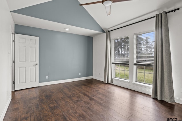 spare room featuring dark wood-style floors, vaulted ceiling, baseboards, and a ceiling fan