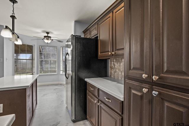 kitchen featuring stainless steel fridge, decorative light fixtures, marble finish floor, light countertops, and dark brown cabinets