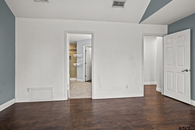 unfurnished room featuring dark wood-style floors, visible vents, and baseboards