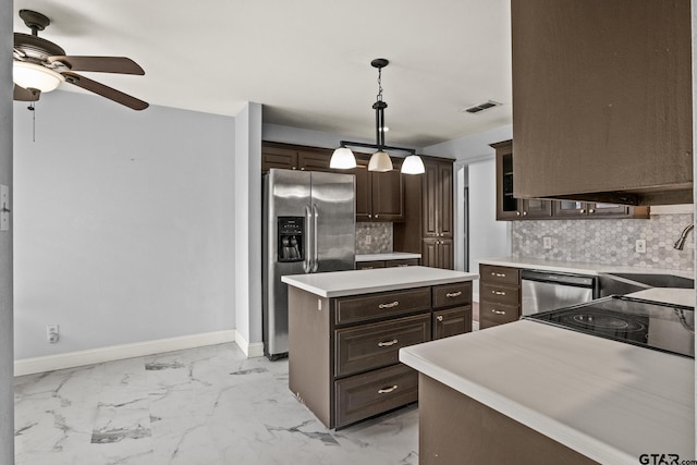 kitchen with a kitchen island, light countertops, appliances with stainless steel finishes, dark brown cabinets, and pendant lighting