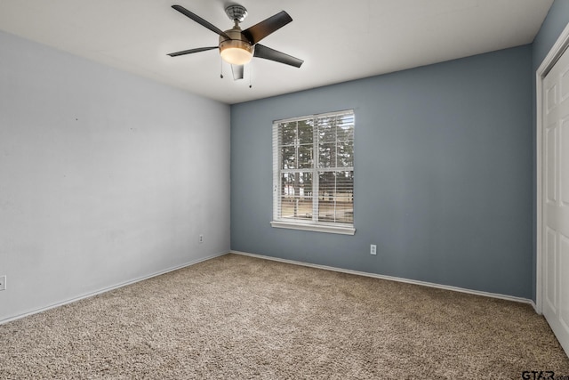 carpeted spare room with ceiling fan and baseboards