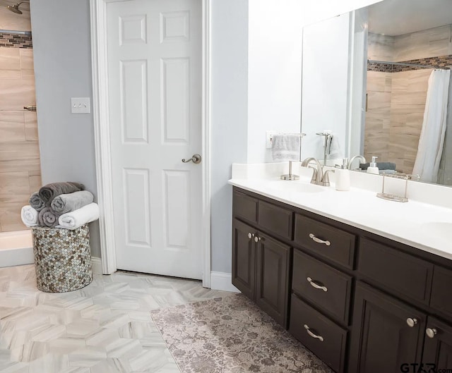 bathroom with tiled shower and vanity