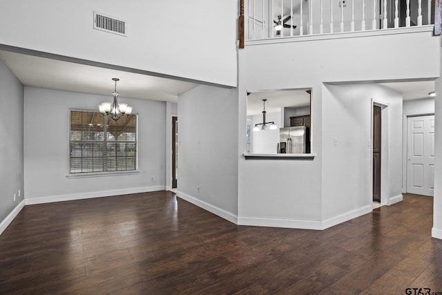 interior space with a high ceiling, visible vents, baseboards, dark wood-style floors, and an inviting chandelier