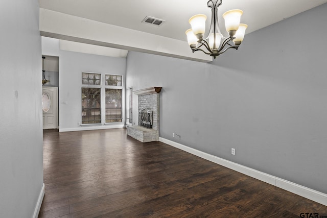 unfurnished living room with a fireplace, visible vents, baseboards, dark wood finished floors, and an inviting chandelier