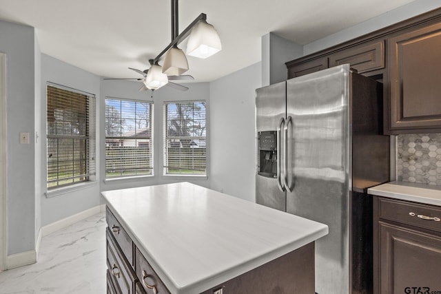 kitchen with baseboards, marble finish floor, dark brown cabinets, light countertops, and stainless steel fridge