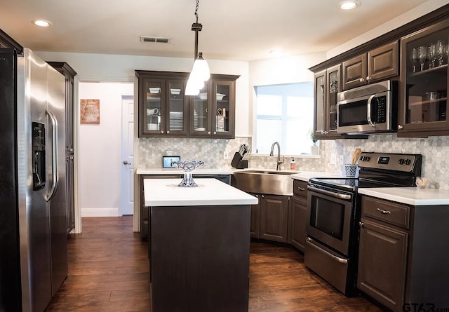 kitchen featuring stainless steel appliances, dark hardwood / wood-style floors, decorative light fixtures, a kitchen island, and sink