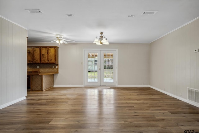 unfurnished living room featuring ceiling fan with notable chandelier, dark wood-type flooring, ornamental molding, and french doors