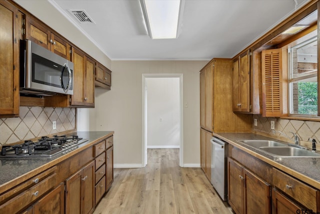 kitchen featuring sink, decorative backsplash, ornamental molding, stainless steel appliances, and light wood-type flooring