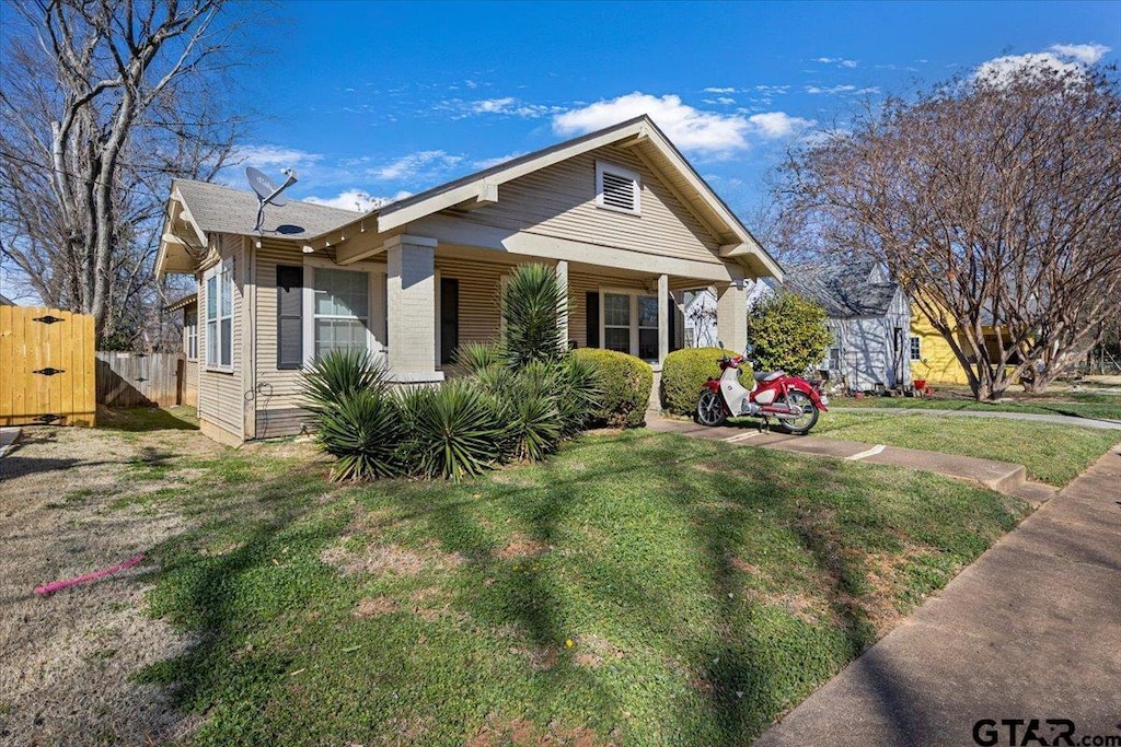 bungalow-style home with a gate, fence, and a front lawn