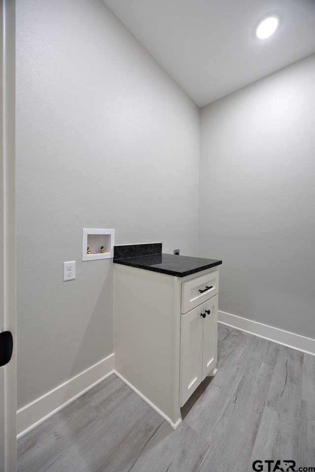 laundry area with cabinets, hookup for a washing machine, and light wood-type flooring