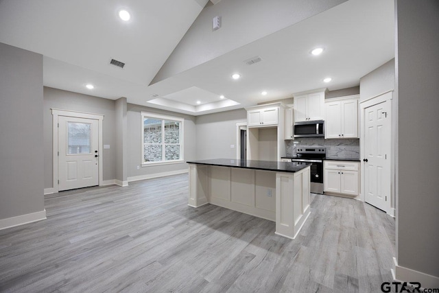 kitchen with appliances with stainless steel finishes, white cabinets, and light hardwood / wood-style flooring