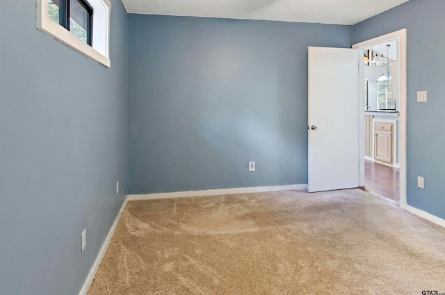 carpeted empty room featuring a chandelier