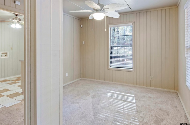 carpeted empty room with wood walls and ceiling fan