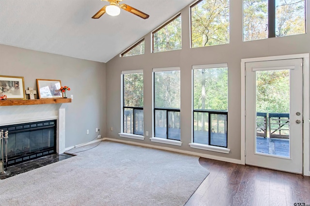 unfurnished living room featuring a fireplace, dark hardwood / wood-style floors, ceiling fan, and high vaulted ceiling