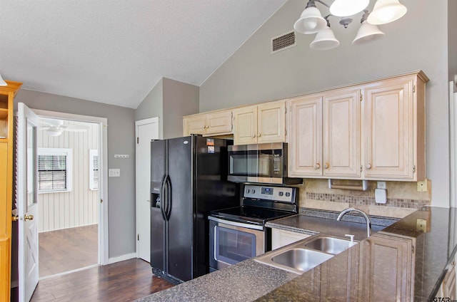 kitchen featuring stainless steel appliances, vaulted ceiling, sink, dark hardwood / wood-style floors, and backsplash