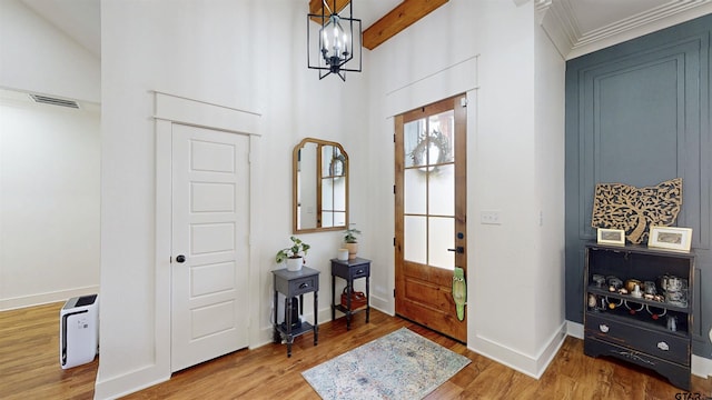 foyer entrance with baseboards, visible vents, wood finished floors, and a notable chandelier