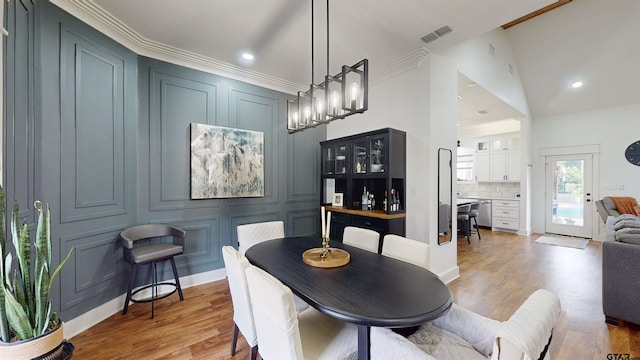dining space with light wood-style floors, a decorative wall, recessed lighting, and visible vents