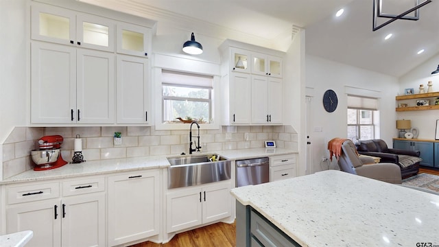 kitchen featuring decorative backsplash, white cabinetry, light stone counters, a sink, and light wood finished floors