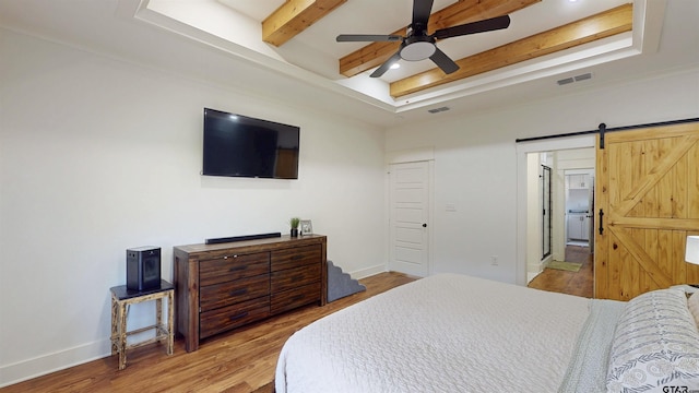 bedroom featuring visible vents, a raised ceiling, and wood finished floors