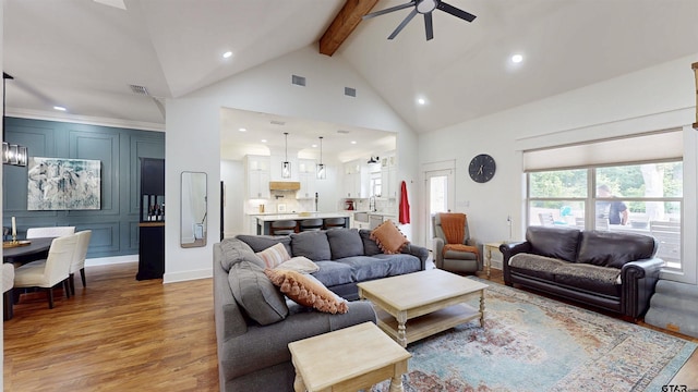 living area with beamed ceiling, ceiling fan, high vaulted ceiling, recessed lighting, and light wood finished floors