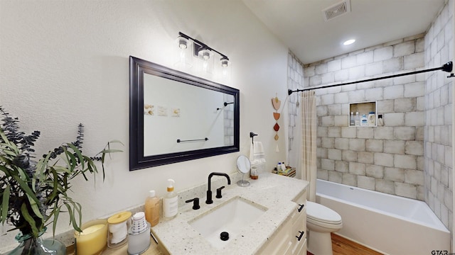full bath with visible vents, vanity, wood finished floors, toilet, and shower / tub combo