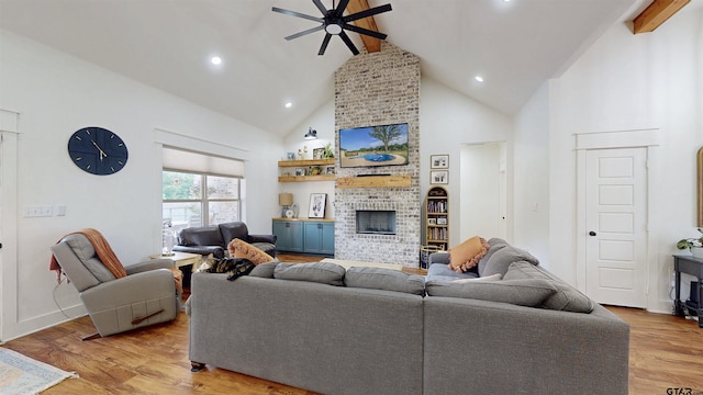 living room with a fireplace, high vaulted ceiling, light wood-style flooring, a ceiling fan, and beamed ceiling