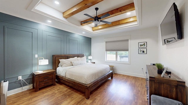 bedroom with baseboards, recessed lighting, a tray ceiling, a ceiling fan, and light wood-style flooring