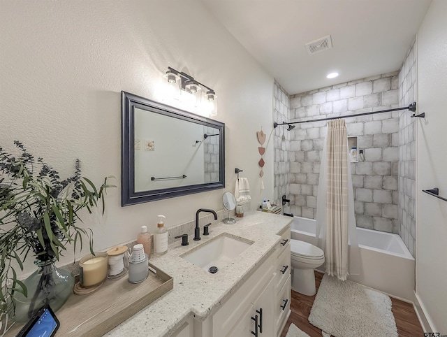 bathroom with visible vents, wood finished floors, vanity, toilet, and shower / bath combo with shower curtain