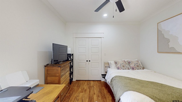 bedroom featuring crown molding, ceiling fan, wood finished floors, and a closet