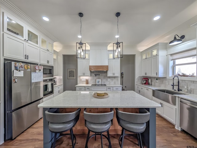 kitchen with a sink, appliances with stainless steel finishes, backsplash, and a kitchen island