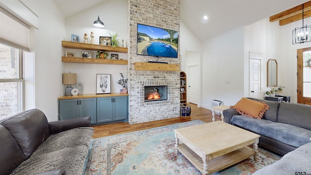 living area with a brick fireplace, high vaulted ceiling, a notable chandelier, light wood-style floors, and recessed lighting