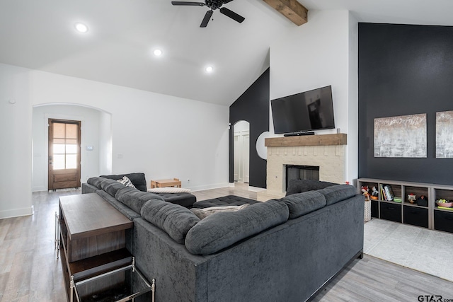 living room featuring a brick fireplace, hardwood / wood-style flooring, beamed ceiling, and high vaulted ceiling