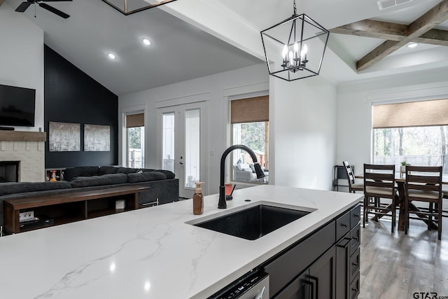 kitchen featuring light hardwood / wood-style floors, hanging light fixtures, sink, beamed ceiling, and light stone countertops