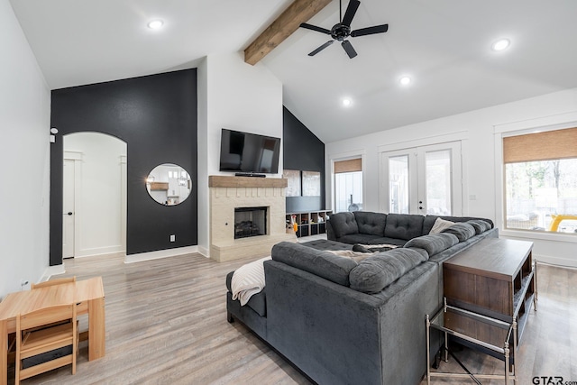 living room featuring a fireplace, ceiling fan, beam ceiling, and light hardwood / wood-style flooring