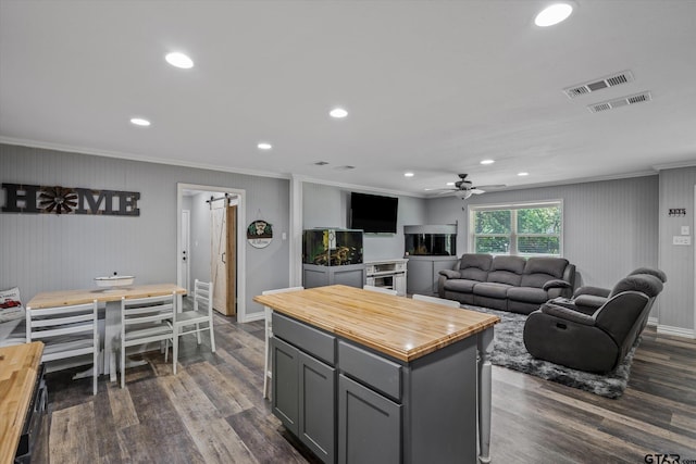 kitchen featuring crown molding, a kitchen island, a barn door, gray cabinets, and dark wood-type flooring