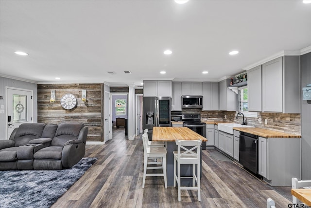 kitchen with stainless steel appliances, a kitchen island, wood counters, sink, and hardwood / wood-style floors