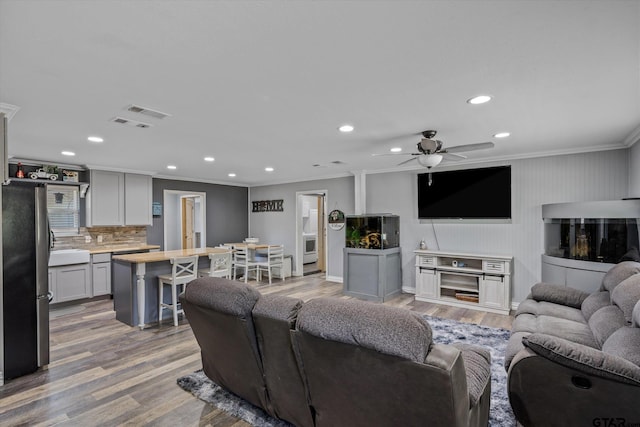 living room featuring ceiling fan, light hardwood / wood-style flooring, and crown molding