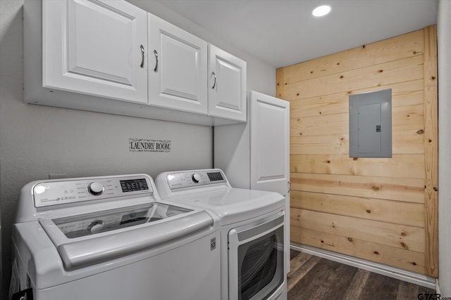 laundry room featuring electric panel, dark hardwood / wood-style floors, cabinets, wooden walls, and washing machine and dryer