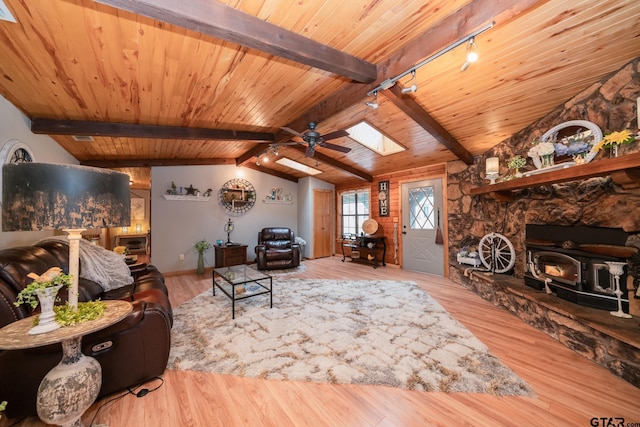 living room with rail lighting, a wood stove, wooden ceiling, vaulted ceiling with skylight, and light hardwood / wood-style floors