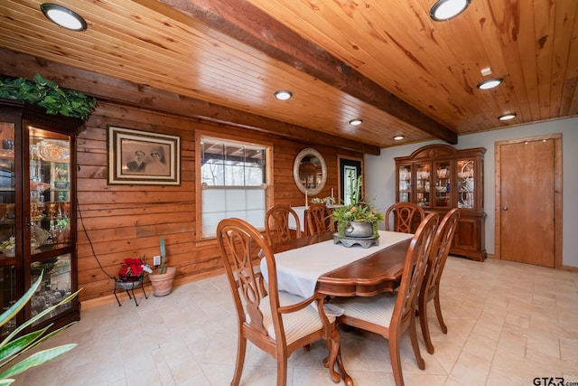 dining space featuring beam ceiling, wooden ceiling, and wood walls