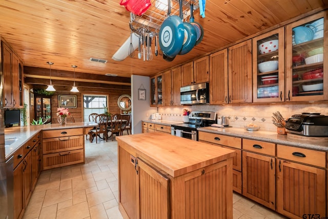 kitchen with butcher block counters, wood ceiling, hanging light fixtures, appliances with stainless steel finishes, and a kitchen island