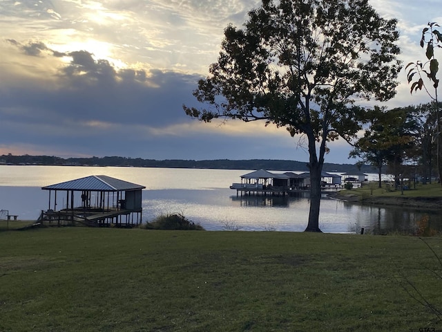 view of dock with a lawn and a water view