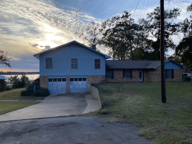 tri-level home featuring a garage and a lawn