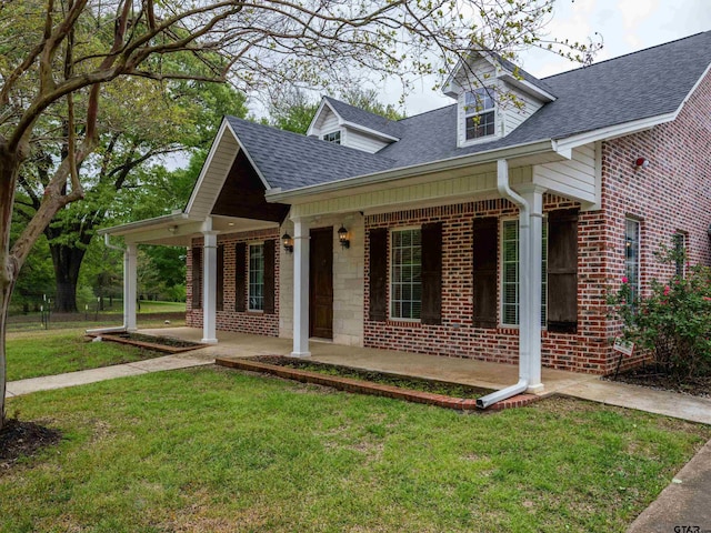 cape cod home featuring stone siding, covered porch, a shingled roof, and a front lawn