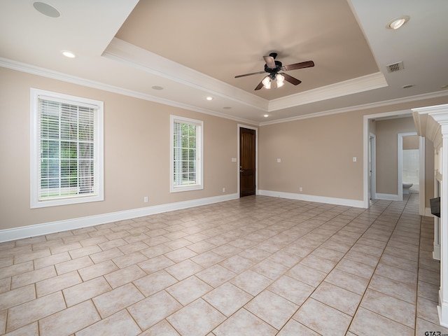 unfurnished room with a ceiling fan, plenty of natural light, a tray ceiling, and visible vents