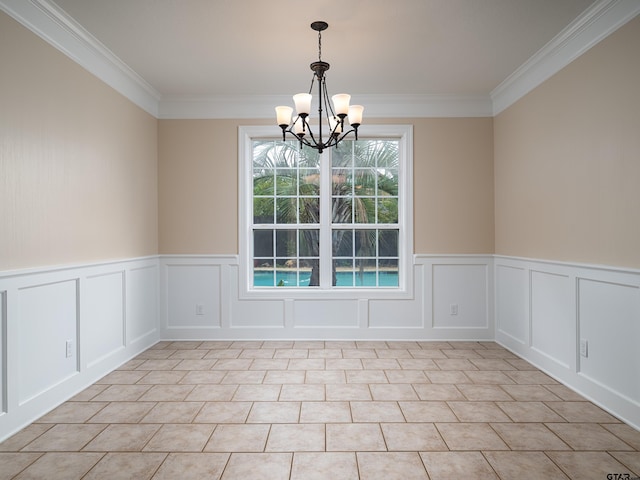 empty room featuring an inviting chandelier, crown molding, and wainscoting
