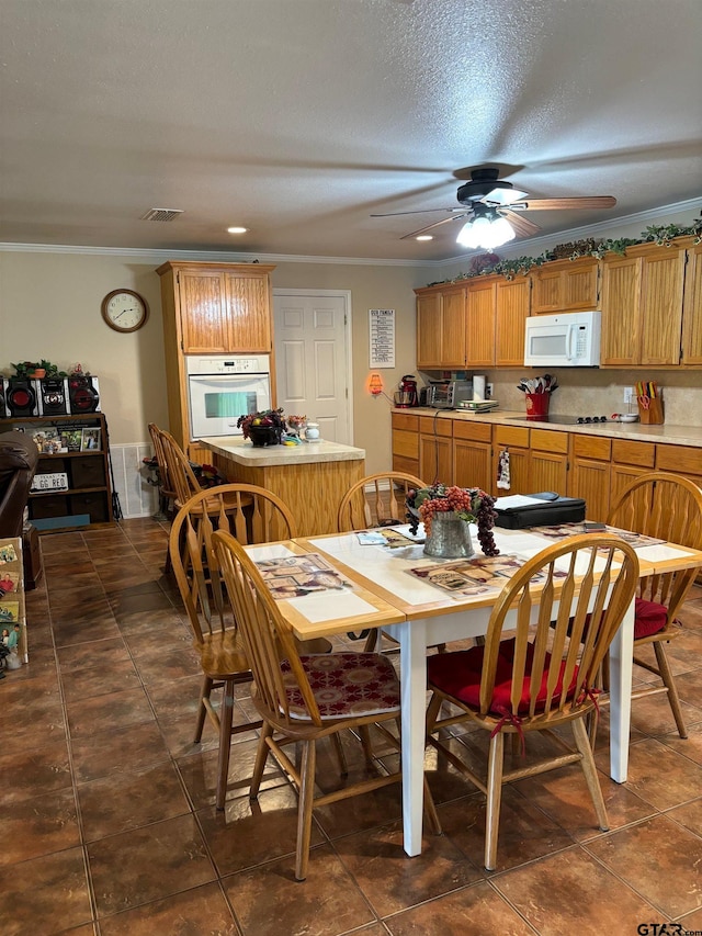 dining room featuring dark tile patterned floors, a textured ceiling, ceiling fan, and crown molding