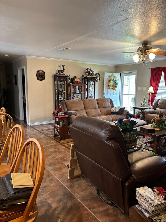 living room featuring ceiling fan, a textured ceiling, dark tile patterned floors, and crown molding